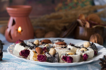 Assorted Turkish delight on a white plate. Traditional yellow, white and black sweets with nuts. Goodies