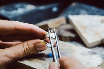Jeweler setting a precious stone with pincers on a ring