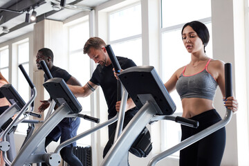 group of fitness people training on cross trainer in modern gym, diverse people enjoy being involved in sport, fitness