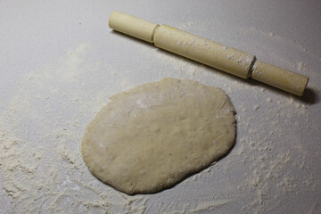 table sprinkled with flour on which lies a rolling pin and dough