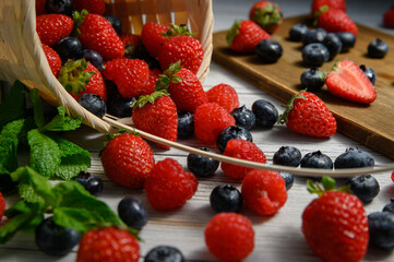 The berries spill out of the basket. strawberries and blueberries