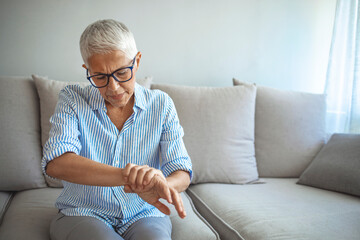 Elderly lady is enduring strong ache. Elderly woman suffering from pain in hand, closeup. Elderly...