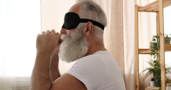 Senior Man Sleeping With Eye Mask On Bed At Home