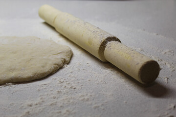 table sprinkled with flour on which lies a rolling pin and dough