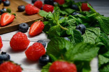 blueberries and strawberries on a white plate with mint sprigs close-up