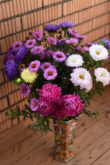 Beautiful colorful bright bouquet of asters large and small in a tall vase. Vertical photo.
