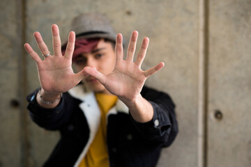 Defocused young boy portrait with hands in front of him to say stop or protect - concept of youth...