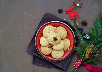 Homemade sugar cookies with cardamom in the New Year and Christmas style on the red clay plate on a brown background concrete.