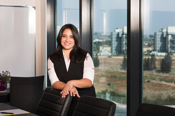 Portrait of beautiful young woman working in office looking and smiling at camera