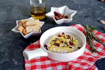 Baked camembert or brie with rosemary, garlic and olive oil. Served with dried cranberries, walnuts