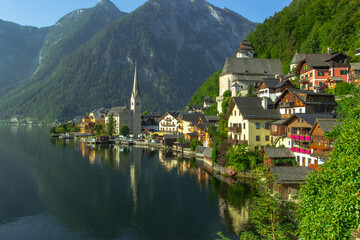 Obraz premium Classic postcard view of famous Hallstatt lakeside town, Austria. Scenic panoramic view of beautiful town reflecting in Hallstatter See.Beautiful sunny day in summer, Salzkammergut region.Urban scene.