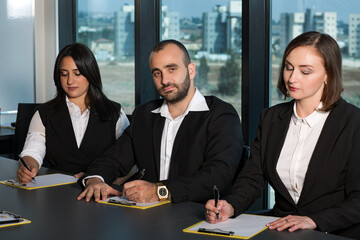 Business people during meeting in board room. Colleagues at business meeting in conference room. Always brainstorming. Smiling colleagues working together at desk in office discussing papers