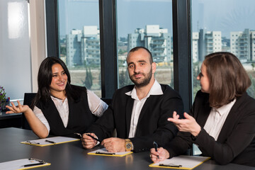 Business people during meeting in board room. Colleagues at business meeting in conference room. Always brainstorming. Smiling colleagues working together at desk in office discussing papers