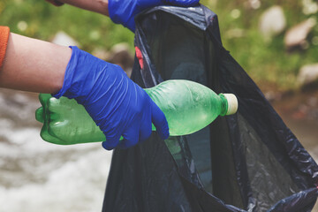 volunteer young woman collecting plastic bottle garbage, picking up waste, land and water...