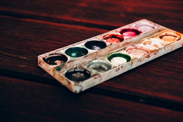 Art Palette with empty Colorful Paints Close up on a mahogany table. Empty and used multi-colored paint.