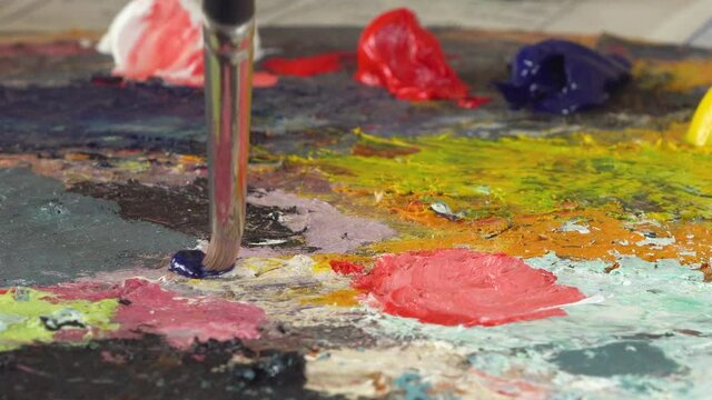 Mixing colors on paint palette with paint brush, close-up