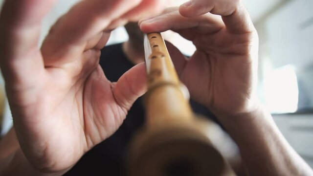 male musician hands playing on recorder, woodwind wood flute