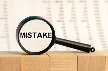 a magnifying glass against columns of numbers background increases the word MISTAKE