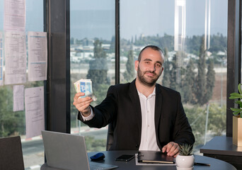 Confident businessman in suit holding a bunch of money cash ILS shekels. Time investment, wage,...