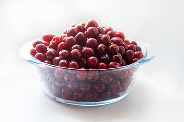 Fresh ripe cherry in a plate on the white background. Top view, copy space. Harvesting red cherries in season.