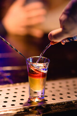 Bright cocktails - shots at the bar. Colorful footage in a nightclub. Alcoholic drink of different colors. Nightlife scene. Shots at the bar table. Several glasses of alcohol 