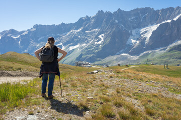 une femme avec un sac à dos et des bâtons admire un paysage de montagne
