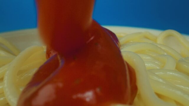 Ketchup pouring on spaghetti with on blue background, taking macro shot pasta on plate with Laowa Lens