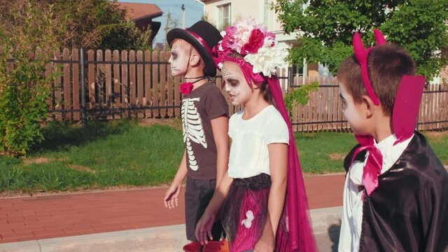 Tracking shot of children in halloween costumes carrying baskets and walking in suburban neighborhood