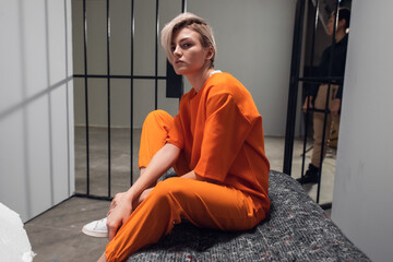 A young pretty blonde prisoner in a general regime prison is sitting in a solitary cell.