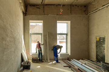 Drywall installation work in progress by construction workers at construction room. Construction...