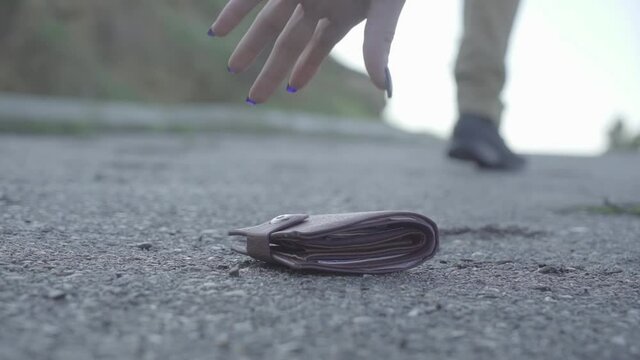 Wallet with money drop on the street, lost money concept, Lost leather wallet and walking male legs, outdoors