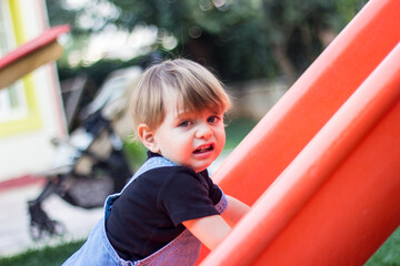 Fototapeta na wymiar a child crying while climbing to a slide in a park