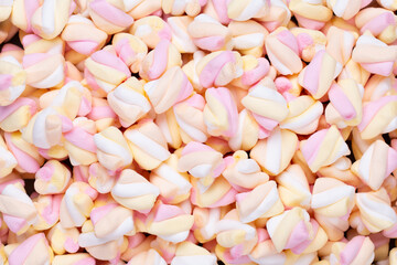 Marshmallows on blue background with copyspace. Flat lay or top view. Background or texture of colorful mini marshmallows.