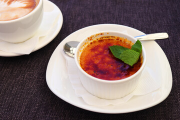 Delicious creme brulee dessert on a white plate close up. Traditional french dessert. Selective focus