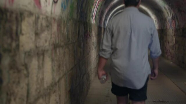 Disoriented Man walks through underground tunnel