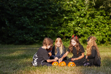 Wide angle portrait of multi-ethnic group of children eating candy on Halloween outdoors while wearing costumes, copy space