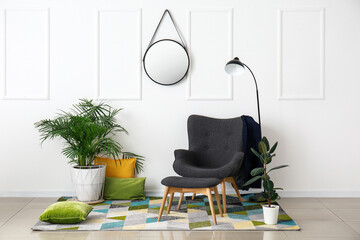 Interior of room with stylish armchair and houseplants near white wall