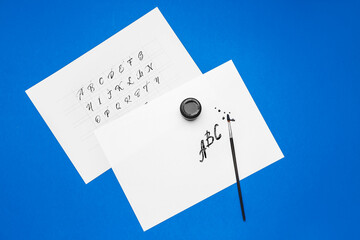Supplies for calligraphy practice on color background