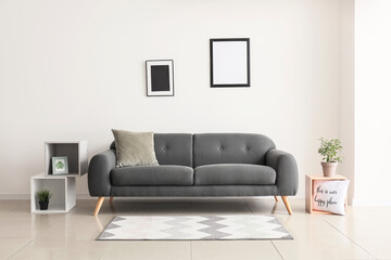 Comfortable sofa near white wall in room