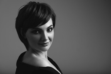 Black and white portrait of young woman with beautiful short hair on dark background