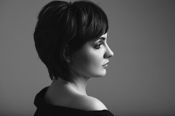 Black and white portrait of young woman with beautiful short hair on dark background