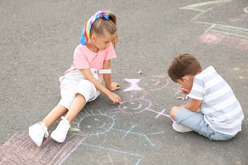 Naklejka premium Little children drawing with chalk on asphalt