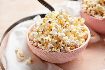 Bowl of tasty popcorn on color background