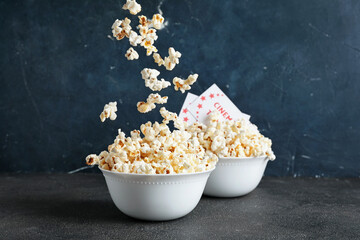 Bowls of tasty popcorn with cinema tickets on dark background