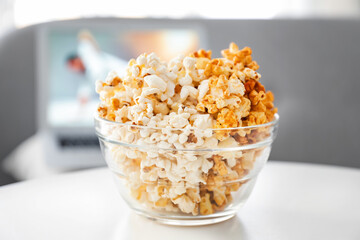 Bowl of tasty popcorn on table at home