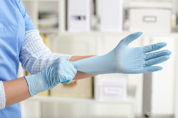 Doctor putting on medical gloves in clinic