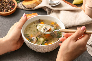 Woman eating tasty rice soup at table