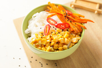 Bowl with tasty rice noodles and vegetables on table