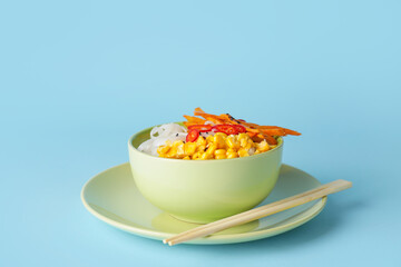 Bowl with tasty rice noodles and vegetables on color background