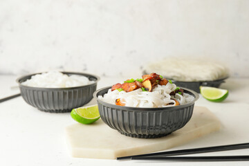 Bowl with tasty rice noodles and meat on white background